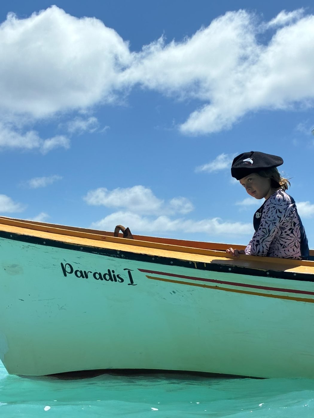 Béret noir Lagardette porté en barque, sur une mer turquoise